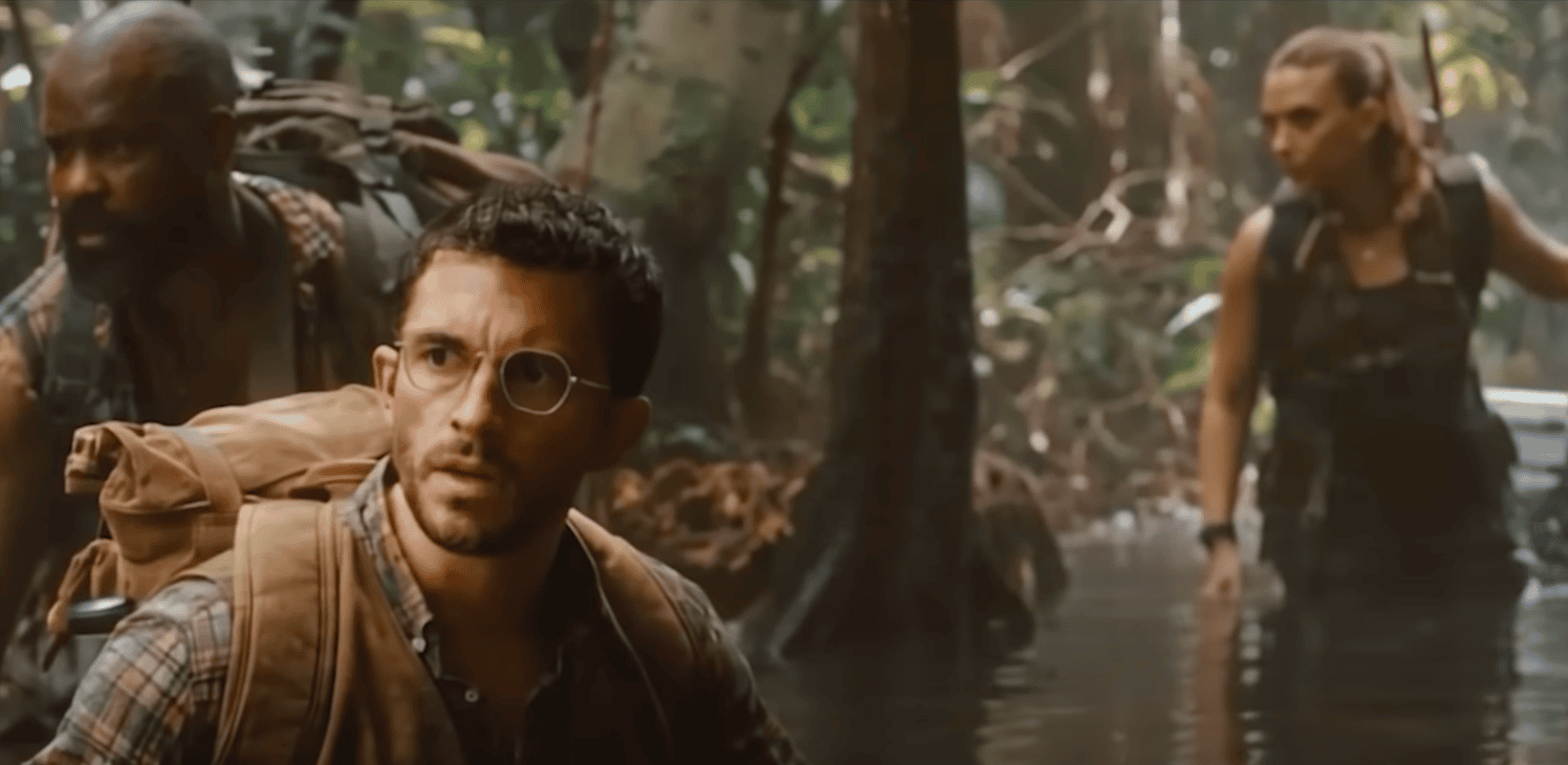 film still from Jurassic World showing three characters trekking through the jungle