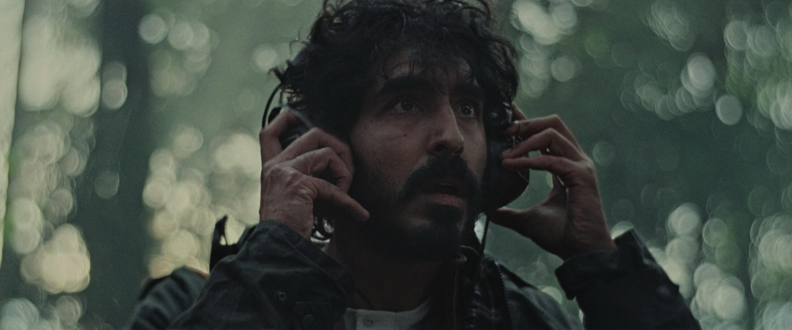 film still showing Dev Patel looking concerned with headphones on