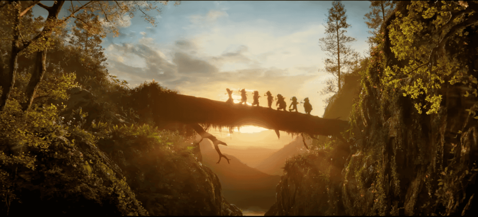 film still from Snow White showing the seven dwarves walking across a tree trunk