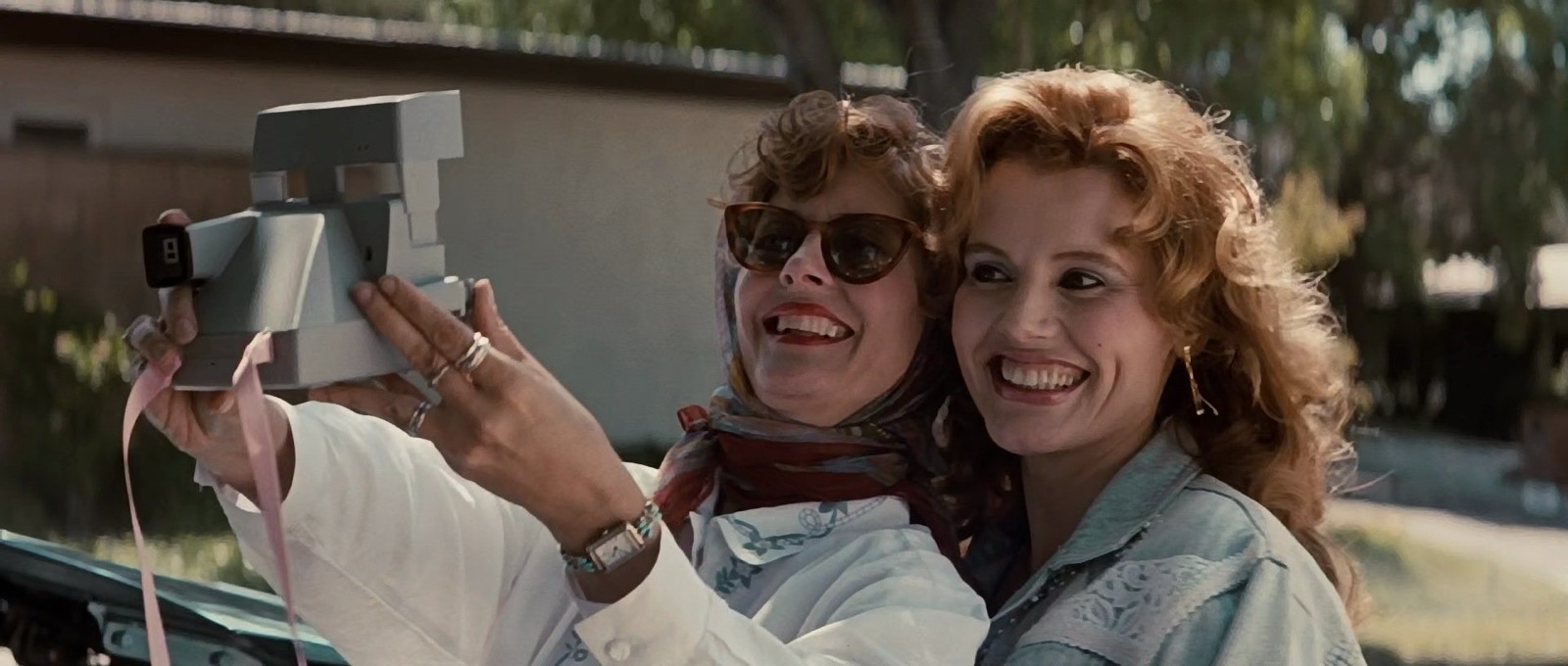 Film still from Thelma & Louise (1991) showing two women taking a photograph of themselves with a polaroid camera 