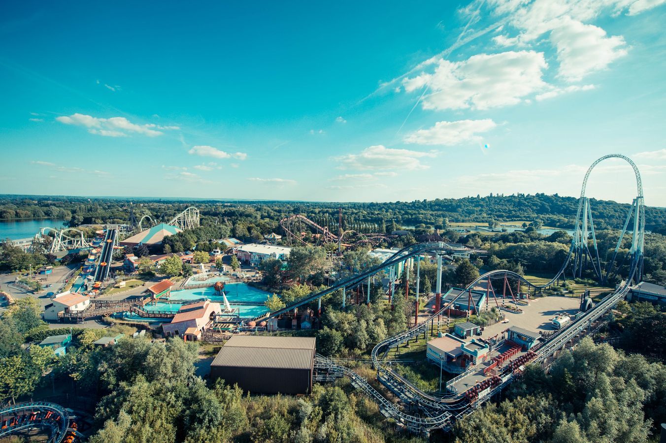Aerial view of a major theme park with rollercoasters, rides and a lake in Surrey