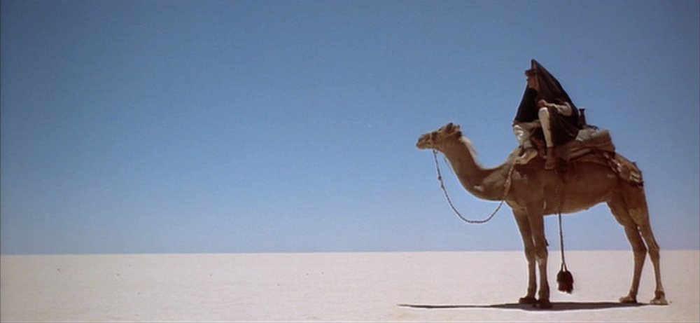Film still from Lawrence of Arabia (1962) showing a man riding a camel in the desert by British director David Lean