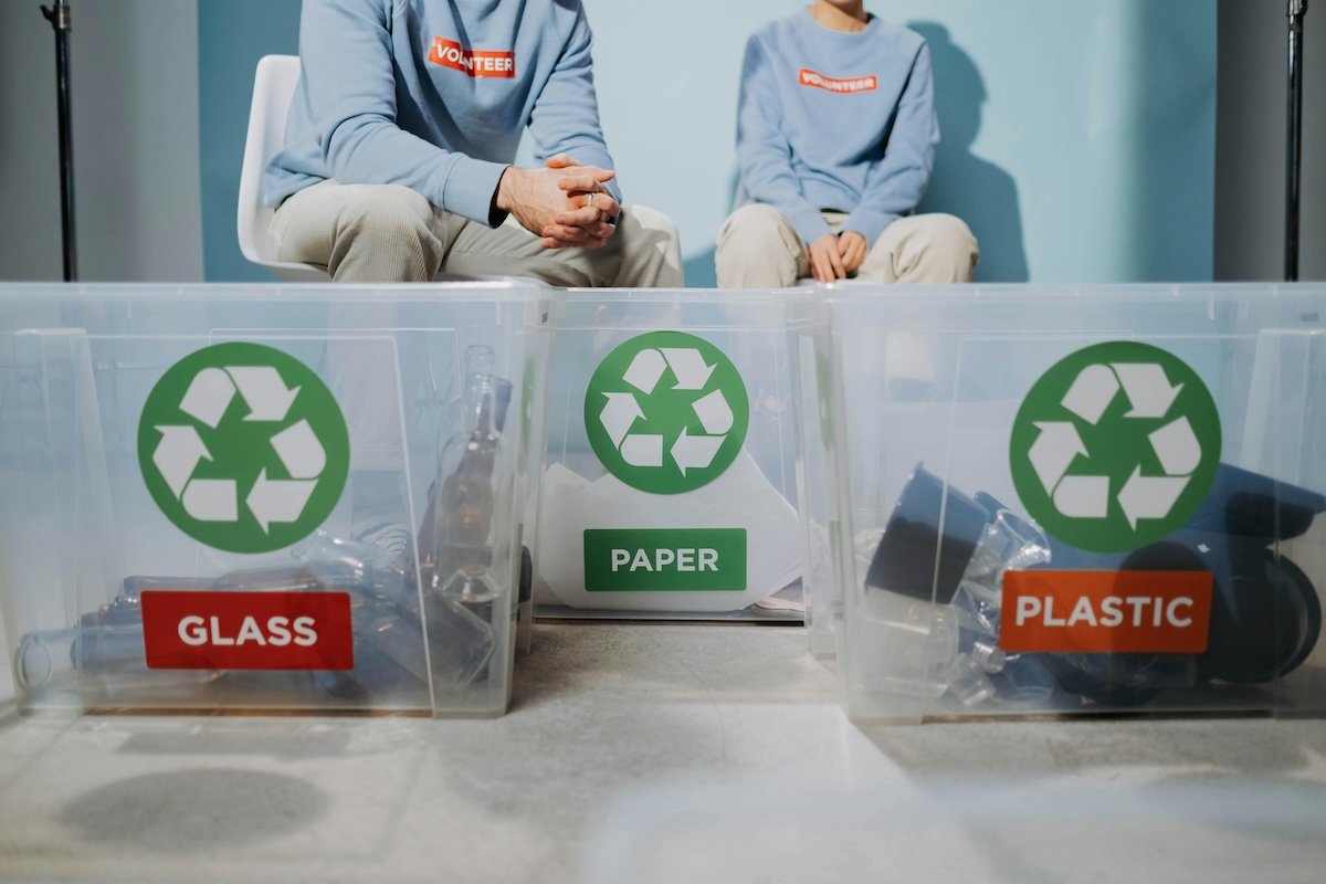 an image of glass, paper and plastic recycling bins