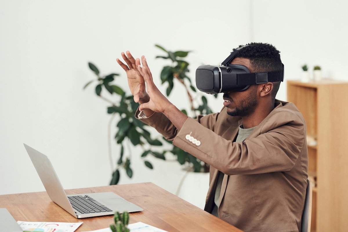 sustainable film: an image of a man sitting in front of his laptop, wearing a Virtual Reality headset
